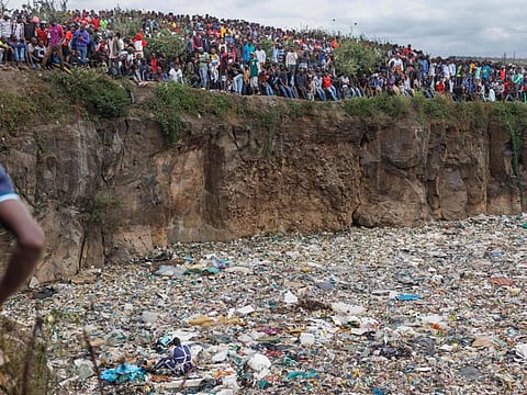 People look on as a volunteer searches through a rubbish dump for human remains at Mukuru slum in Nairobi on July 14, 2024.