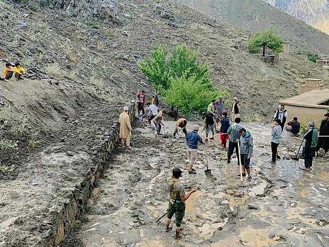 Afghan residents shovel mud following flash floods after heavy rainfall at Pesgaran village in Dara district, Panjshir province on July 15, 2024.