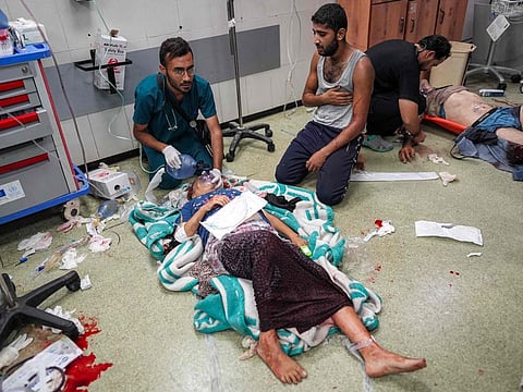 A medic helps an injured victim breathe through an oxygen mask while lying on the flood at a trauma ward at Nasser Medical Complex in Khan Younis in the southern Gaza Strip on July 16,