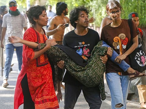 Students carry a wounded woman after anti-quota protesters and students backing the ruling Awami League party clashed on Dhaka University campus in Dhaka.