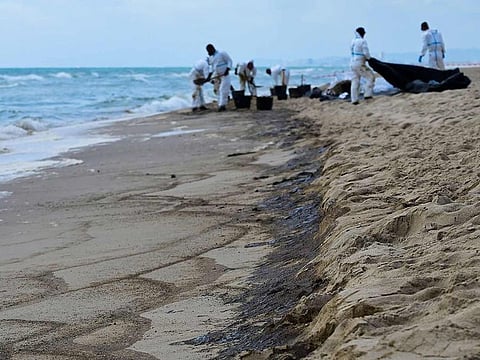 Technicians work to clean up the El Saler beach in the Albufera Natural Park, after the city council of Valencia closed three beaches on the Mediterranean coast following a suspected oil or fuel spill on the sand, in Valencia on July 17, 2024.