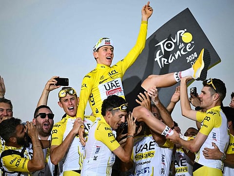 UAE Team Emirates team's Slovenian rider Tadej Pogacar celebrates his overall victory on the podium with teammates and staff on Sunday.