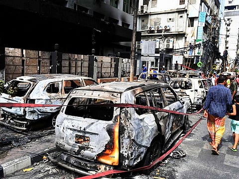 Burnt vehicles cordoned off on a roadside in Dhaka after protesters set them on fire.