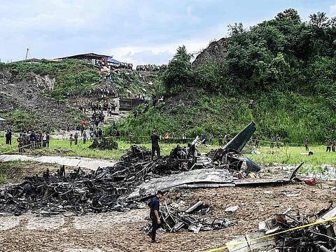 Rescuers and officials stand at the crash site after a Saurya Airlines' plane crashed during takeoff at the Tribhuvan International Airport in Kathmandu on July 24, 2024.