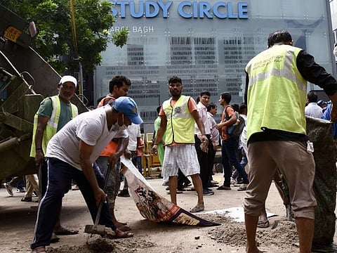 Delhi Municipal Corporation (MCD) workers outside the Rau’s IAS Study Centre in Old Rajinder Nagar, New Delhi, on July 28, 2024, amid a student protest following the deaths of three civil service aspirants who drowned in the coaching centre's basement due to flooding.