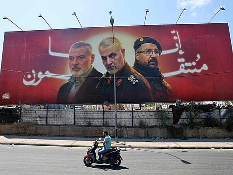 A man rides his moped past a billboard bearing portraits of slain leaders, Ismail Haniyeh of the Palestinian militant group Hamas, Iranian Quds Force chief Qasem Soleimani (centre), and Hezbollah senior commander Fuad Shukr on the main road near the Beirut International Airport on August 3, 2024.