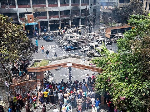 People gather to see the burnt Jatrabari police station after anti-government protestors set it on fire in Dhaka on August 6, 2024.