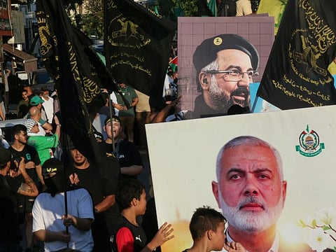 People take part in a march called by Palestinian and Lebanese youth organisations in the southern Lebanese city of Saida, on August 5, 2024, to protest against the assassination of Hamas chief Ismail Haniyeh (portrait bottom) and Hezbollah military commander Fuad Shukur.