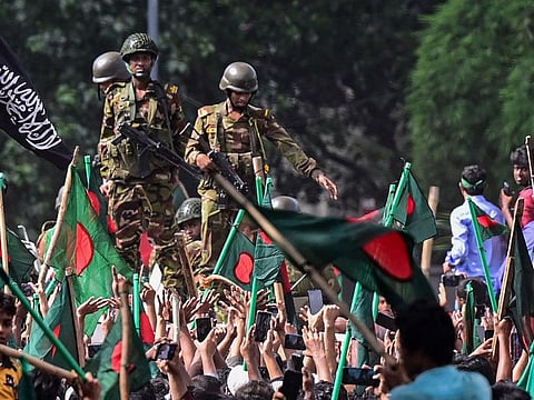 Anti-government protesters march towards Prime Minister Sheikh Hasina's palace as army personnel stand guard in Shahbag area, near Dhaka university in Dhaka on August 5, 2024.