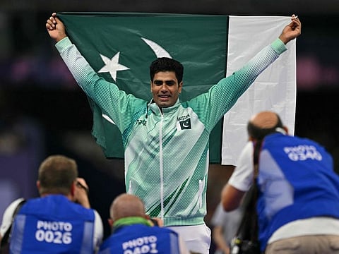 Pakistan's Arshad Nadeem poses with his national flag as he celebrates his gold medal-winning effort in the men's javelin in Paris Olympic Games.