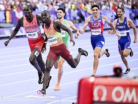 Silver medallist Canada's Marco Arop (left) and Gold medallist Kenya's Emmanuel Wanyonyi (centre) cross the finish line in the men's 800m final of the athletics event at the Paris 2024 Olympic Games at Stade de France in Saint-Denis, north of Paris, on August 10, 2024.