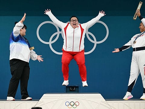 China's gold medallist Li Wenwen celebrates as South Korea's silver medallist Hyejeong Parkand (left) and Britain's bronze medallist Emily Campbell watch during the victory ceremony of the women's +81kg weightlifting event during the Paris 2024 Olympic Games at the South Paris Arena in Paris, on Sunday.