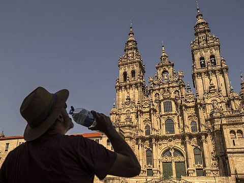 A tourist drinks water in front of the Cathedral of Santiago during high temperatures in Santiago de Compostela, Spain.