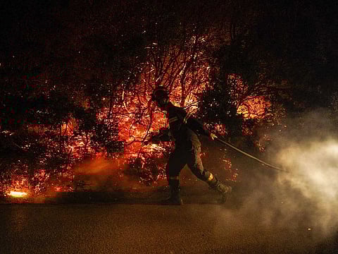 Firefighters and volunteers work to control the East Attica wildfire in Varnavas, northeast of Athens, Greece.