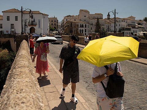 Tourist hide from the sun with umbrellas as their visit Ronda, southern Spain as the country faces the fourth heatwave of the summer, on August 9, 2024. (Photo by JORGE GUERRERO / AFP)