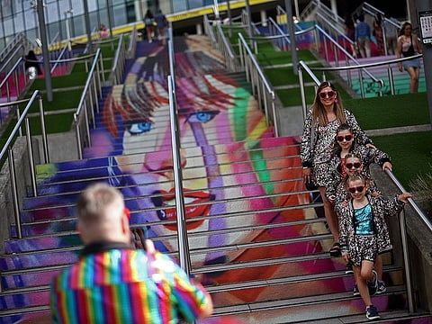 Fans of US mega-star Taylor Swift, so-called "Swifties", pose for a photograph in front of the 'Swiftie Steps' a mural created by the British artist Frank Styles, outside Wembley Stadium in London on August 15, 2024, ahead of the first of five concerts she is playing at the stadium.