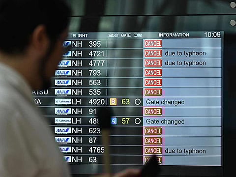 A TV news crew team works in front of a screen showing cancelled flights at the departure hall of Tokyo's Haneda Airport on August 16, 2024 as Typhoon Ampil barrels towards Japan's capital.