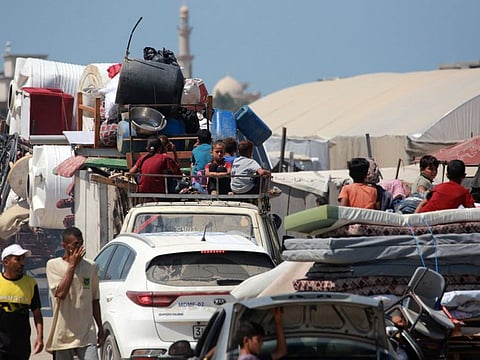 Palestinians flee a makeshift camp for displaced people in Khan Yunis in the southern Gaza Strip after Israeli tanks took position on a hill overlooking the area on August 18, 2024.