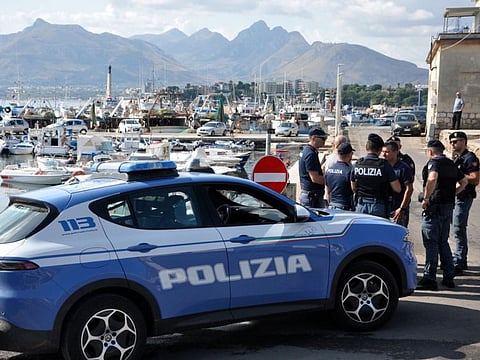 Italian police officers stand at the port as the search continues for six passengers missing from a sailboat that sank off the coast of Porticello, north-western Sicily.