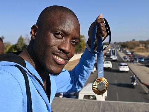 Olympic gold medallist, Botswana's Letsile Tebogo, who won the men's 200m athletics event during the Paris 2024 Olympic Games, holds his gold medal as he travels on an open bus during a welcoming ceremony in Gaborone on August 13.
