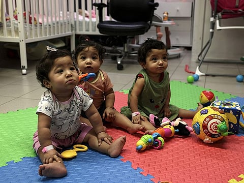 Palestinian triplets of Gaza-native Hanane Bayouk, Najmeh (L), Najoua (C) and Noor, play at the children's ward of the Al Maqased Hospital in east Jerusalem on July 31, 2024.