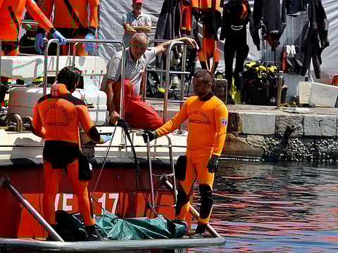 Divers of the Vigili del Fuoco, the Italian Corps. of Firefighters enter Porticello harbor near Palermo, with the body of the last missing person at the back of the boat.