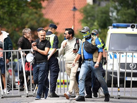 Protester Salwan Momika (centre) is escorted by police to a location outside the Iraqi Embassy in Stockholm, Sweden, on July 20, 2023, where he burnt a copy of the Quran and the Iraqi flag.