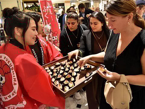 A customer (R) trying peaches from Japan's Fukushima prefecture, which went on sale at luxury department store Harrods in central London.
