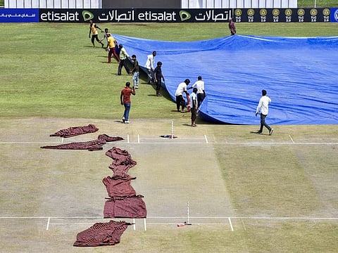 Ground staff cover the wet outfield during Day 2 of the one-off test between Afghanistan and New Zealand, at Shahid Vijay Singh Pathik Sport Complex, in Greater Noida on Tuesday.