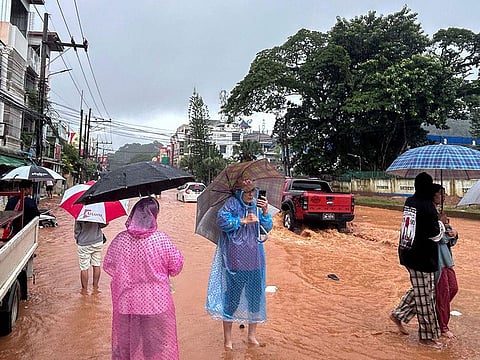 People hold umbrellas in the rain as they stand in flood waters in Tachileik in Myanmar's eastern Shan state.