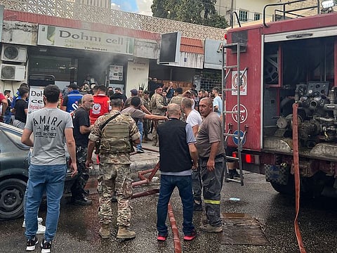 People and first responders gather at the scene of a reported device explosion in Saida in southern Lebanon.