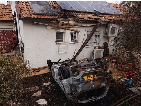 An upturned vehicle in front of a damaged property following missile strikes from Lebanon, on a residential neighborhood, in Moreshet, northern Israel.