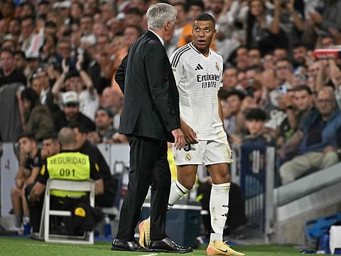 Real Madrid's French forward Kylian Mbappe talks with coach Carlo Ancelotti as he leaves the pitch during the Spanish league football match against Deportivo Alaves at the Santiago Bernabeu stadium in Madrid on September 24.