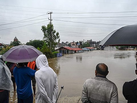 Residents stand along a street as they inspect flood waters after the Bagmati river overflowed during monsoon rains in Kathmandu on September 28, 2024.