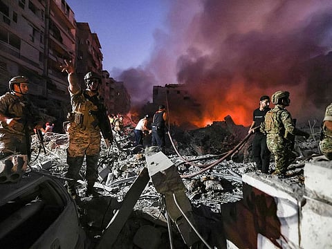 Lebanese army soldiers gather over the rubble of a levelled buildings as people flight the flames, following Israeli air strikes in the Haret Hreik neighbourhood of Beirut's southern suburbs.