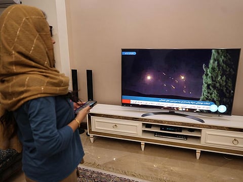 An Iranian woman looks at a television displaying the news of attack on Israel, in Tehran on October 1, 2024.