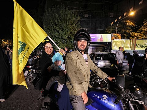 A woman holds the Hezbollah flag while riding behind in a motorcycle with a child, during a rally celebrating after Iran launched a barrage of missiles at Israel in response to the killings of Hezbollah's leader Hassan Nasrallah and other Iran-backed militants outside Imam Jaafar Sadiq Mosque in Tehran's Palestine Square on October 1, 2024.