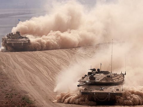 Israeli army tanks drive in an area near Israel's southern border with the Gaza Strip