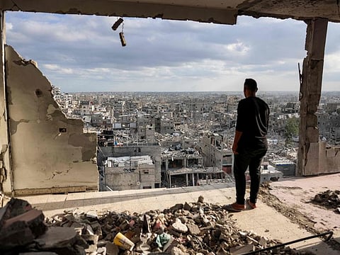 A man standing atop a heavily damaged building views other destroyed buildings in Khan Younis in the southern Gaza Strip on October 7, 2024 on the first anniversary of the ongoing war in the Palestinian territory between Israel and Hamas.