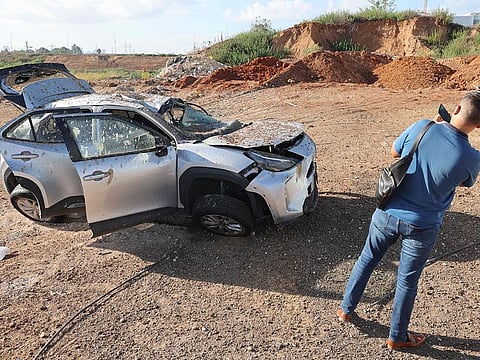 A man takes a picture of a damaged vehicle in the aftermath of an Iranian missile attack on Israel, on October 2, 2024 in Tel Aviv.