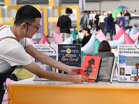 A staff member checks books by South Korean author Han Kang, who won the 2024 Nobel Prize in Literature, displayed during an outdoor library event at Gwanghwamun square in central Seoul on October 11, 2024. From the president to K-pop megastars BTS, South Korea erupted into celebration on October 10, after "The Vegetarian" author Han Kang won the country's first Nobel Prize for literature