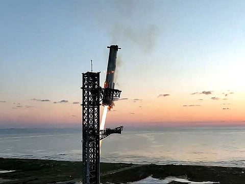 The Starship's Super Heavy Booster being grappled mid-air as it returns to the launch pad at Starbase near Boca Chica, Texas, on October 13, 2024, during the Starship Flight 5 test.