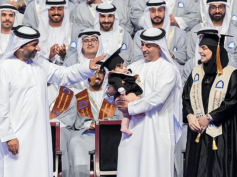 Dr Ahmad Belhoul Al Falasi, Minister of Sports and Chancellor of HCT, carries little Shamsa and her engineer mum Latifa Mohammed Taher Al Marzooqi looks on.