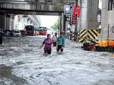 People wade through flooded street amid heavy rainfall, in Chennai on Tuesday.
