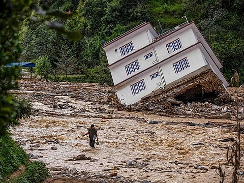 A man wades through the waters in the affected area of monsoon flooding in Roshi village of Nepal's Kavre district