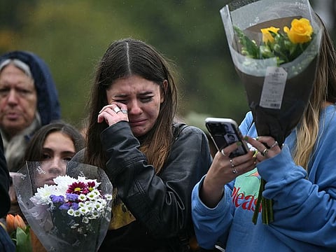 Crying fans of former One Direction singer Liam Payne gather with flowers beside the Peter Pan statue in Kensington Gardens in London.