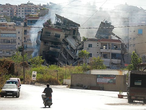 People drive next to a building, targeted in an Israeli airstrike the night before, in Beirut's southern suburbs on October 20, 2024, amid the ongoing war between Hezbollah and Israel.