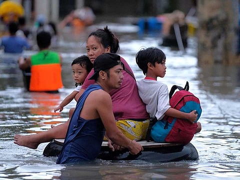 Residents using a makeshift raft wade through a flooded street caused by heavy rains brought about by Tropical Storm Trami in Naga City, Camarines Sur province on October 24, 2024.