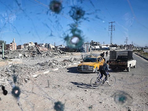 People are seen through the shrapnel-riddled windscreen of a bus that was damaged when an Israeli artillery shell reportedly landed near it on Gaza's main Salah Al Din outside Deir El Balah in the central Gaza Strip on October 24, 2024, amid the ongoing war between Israel and Hamas.