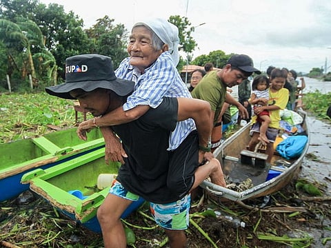 An elderly woman is carried by a volunteer rescuer as residents are evacuated to safer grounds in Bato town, Camarines Sur province South of Manila on October 23, 2024